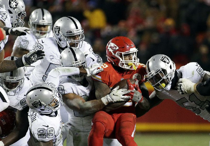 Kansas Chiefs running back Spencer Ware is tackled by linebacker Bruce Irvin (right) and other Oakland Raiders defenders during the Chiefs’ 21-13 victory Thursday night.