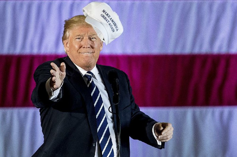 Donald Trump throws a hat into the audience Friday while speaking at a rally in a Dow Chemical hangar at the city airport in Baton Rouge.