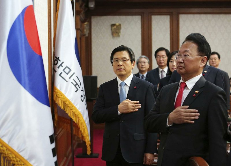 Acting South Korean President Hwang Kyo-ahn (left) salutes the flag Friday during a Cabinet meeting in Seoul.
