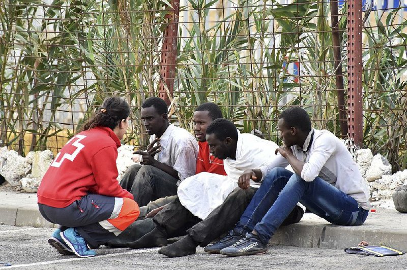 A Red Cross worker speaks with Africans who stormed a fence Friday to enter Ceuta, a Spanish enclave on the North African coast.