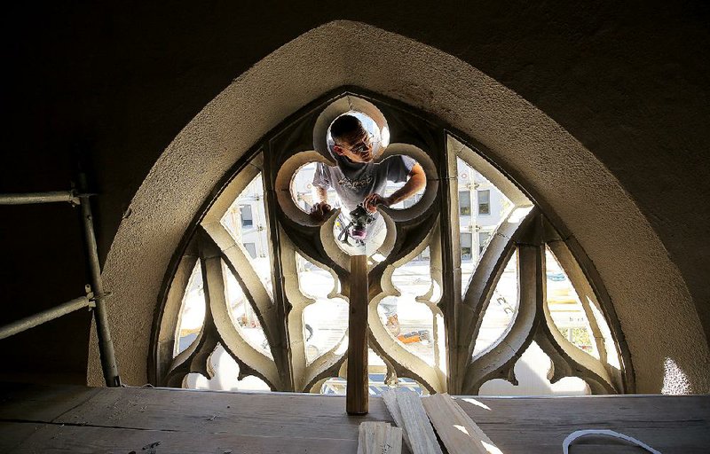 Nathan Cathy, with Soos Stained Glass, talks with a co-worker as he cleans a stained-glass frame during restoration of windows at Christ Episcopal Church in downtown Little Rock. Employees of the North Little Rock company were assisting workers from Franz Mayer of Munich, a company located in Germany.