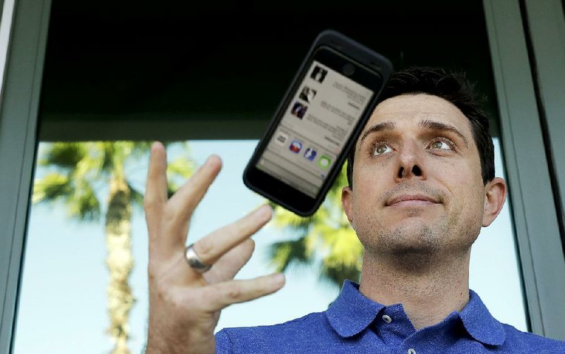 Aaron Norris poses for a picture with his smartphone near his office, in Riverside, Calif., in late November.