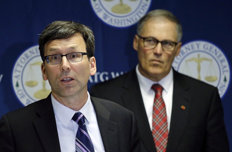 Washington Attorney General Bob Ferguson, left, speaks as Gov. Jay Inslee looks on during a news conference, Thursday, Dec. 8, 2016, in Seattle, where Ferguson announced a lawsuit against agrochemical giant Monsanto over pollution from PCBs, Washington says it's the first U.S. state to sue Monsanto over pollution from PCBs. 