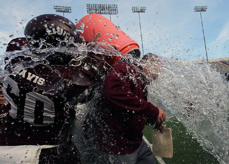 Mount Ida Coach Michael White is doused by offensive lineman Brody Davis after the Lions defeated Hampton in Saturday’s Class 2A championship game at War Memorial Stadium in Little Rock. It was the Lions’ second state championship.