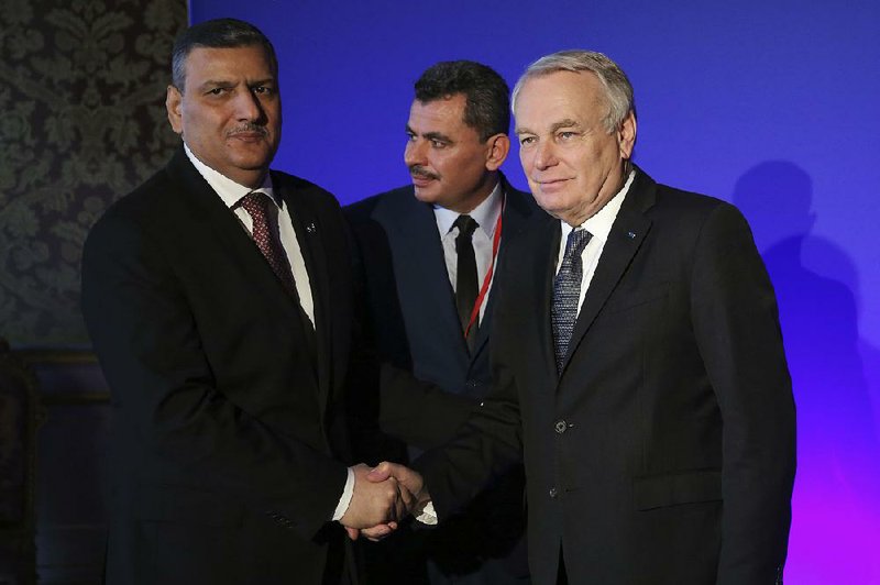 Riyad Hijab (left), chief negotiator for the Syrian opposition, shakes hands with French Foreign Minister Jean-Marc Ayrault on Saturday in Paris as Brita Hagi Hasan (center), president of the Local Council of Aleppo, looks on before a meeting on the crisis in Syria.