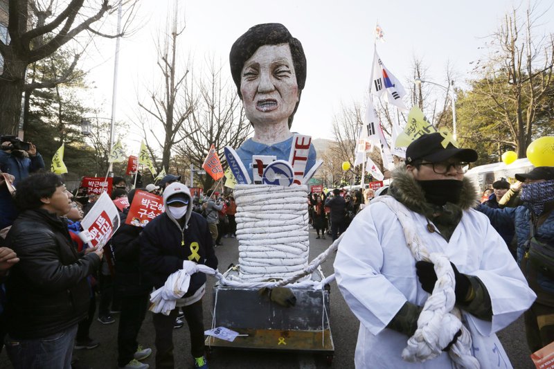Protesters carry an effigy of impeached South Korean President Park Geun-hye as they march toward the presidential house during a rally in Seoul Saturday, Dec. 10, 2016. 