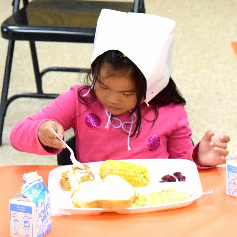 Photo by Mike Eckels Vivienne Vang, a student of Joyce Turnage, gets a scoop of pumpkin desert as she and her classmates enjoy a pre-Thanksgiving meal in Joyce Turnage classroom at Decatur Pre-K school in Decatur Nov. 22. Vang wears a pilgrim bonnet as part of the festivities.