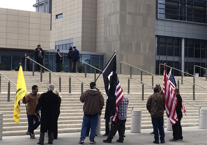 A small group of protesters gather Friday, Dec. 9, 2016, outside the U.S. District Court building in Las Vegas where Nevada rancher Cliven Bundy and 16 other defendants had a hearing before a federal magistrate judge scheduling their trials on charges they conspired to take up weapons against federal agents in an armed standoff in April 2014. 