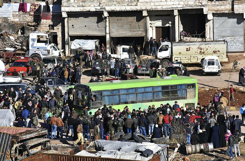 Residents gather near a government bus for evacuation from eastern Aleppo on Thursday, after a cease-fire deal between the Russian military and Syrian rebels was reached.