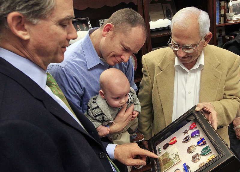 Robert Sangalli (from right), his son-in-law Aaron Appler and grandson Gentry admire medals earned by Sangalli during the Vietnam War. U.S. Rep. French Hill (left) presented Sangalli with the medals Thursday during a surprise ceremony in Little Rock.