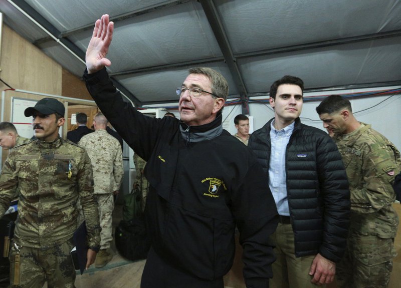 In this Dec. 11, 2016, photo, U.S. Defense Secretary Ash Carter waves to a group of Iraqi and U.S. soldiers during his visit to the Qayara air base, south of Mosul, Iraq. 