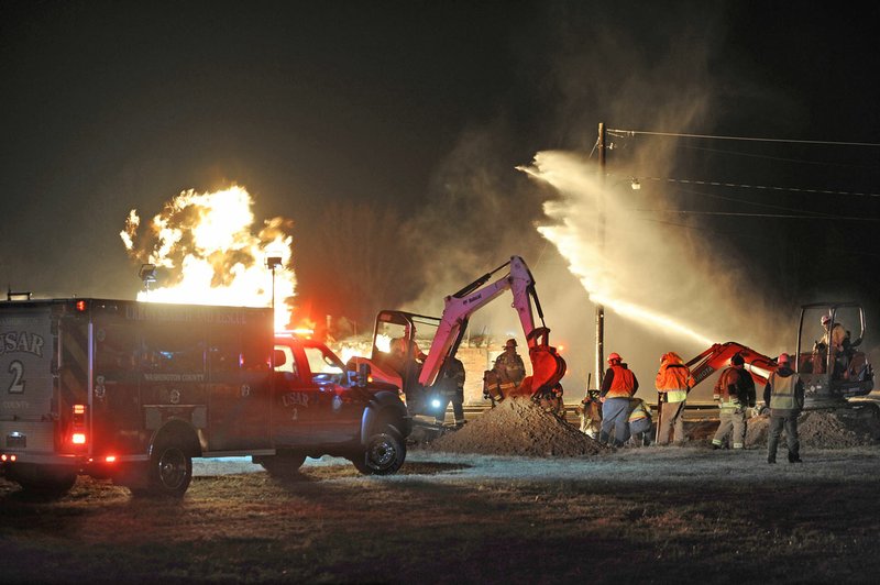 NWA Democrat-Gazette/ANDY SHUPE
Workers with Black Hills Energy work to cut off the flow of natural gas as firefighters from Farmington and Fayetteville fire departments fight to contain the fire after a car struck a natural gas line Friday, Dec. 16, 2016, at Double Springs Road and Main Street in Farmington.  