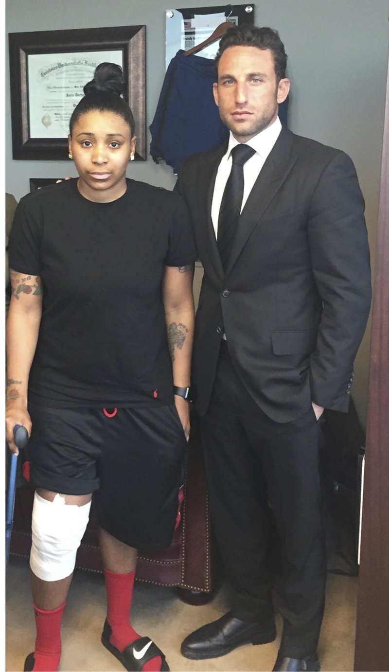 In this April 2016 photo provided by the law office of Lipsig, Shapey, Manus & Moverman P.C., Marc Eli Freund stands next to his client Katrina Williams at the law firm's offices in New York, as she recovers from injuries she said says she got from an exploding e-cigarette. 