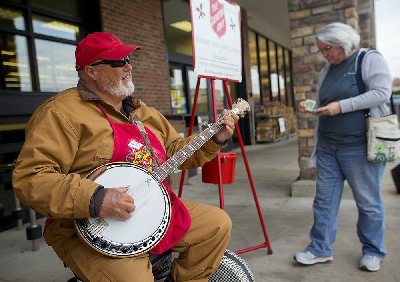 Gary Shipley of Springdale plays his banjo this month outside the Harps Food Store to solicit donations for the Salvation Army.
