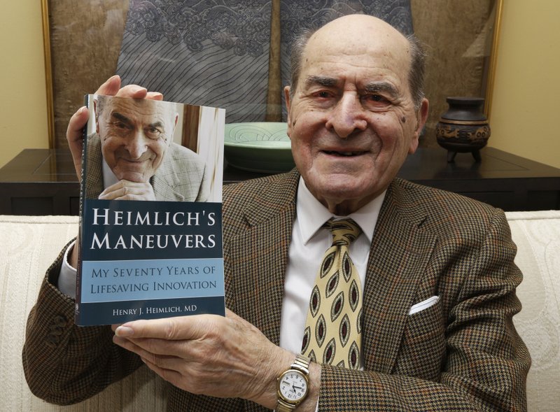 FILE - In this Feb. 5, 2014, file photo, Dr. Henry Heimlich holds his memoir prior to being interviewed at his home in Cincinnati. Heimlich, the surgeon who created the life-saving Heimlich maneuver for choking victims has died Saturday, Dec. 17, 2016, at Christ Hospital in Cincinnati. He was 96. (AP Photo/Al Behrman, File)