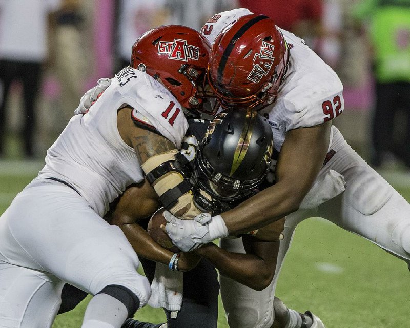 Arkansas State defensive ends Ja’Von Rolland-Jones (left) and Darrius Rosser (right) take down Central Florida quarterback Justin Holman during Saturday’s Cure Bowl. The Red Wolves allowed just 223 yards of offense, forced three turnovers and registered six sacks in beating the Knights 31-13.