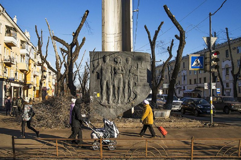 People walk past a Soviet-era monument in Voronezh, a former industrial town.