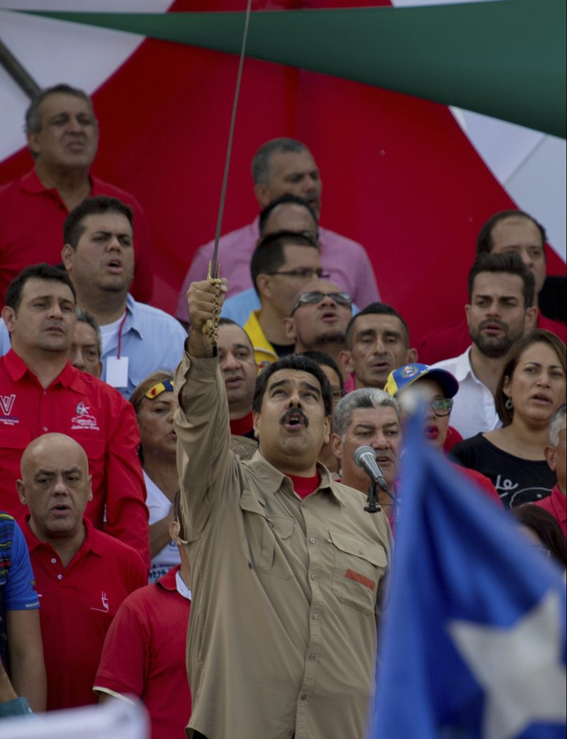Venezuela's President Nicolas Maduro, holds up a sword of Venezuelan hero Simon Bolivar as he sings the national anthem during a rally in Caracas, Venezuela, Saturday, Dec. 17, 2016. 