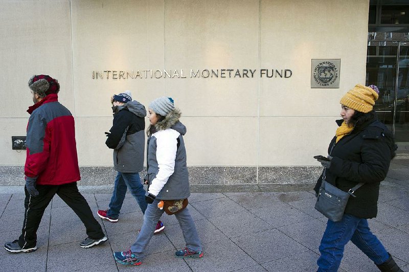 Pedestrians on Monday pass the headquarters of the International Monetary Fund in Washington, D.C. A French court convicted Christine Lagarde, the IMF’s managing director, of negligence for her role in a $425 million arbitration award given to a businessman in 2008, while Lagarde was France’s fi nance minister.