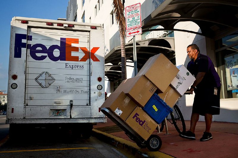 A FedEx driver loads a delivery truck Thursday in Miami. The company Tuesday reported a 20 percent jump in its fiscal second-quarter revenue. 