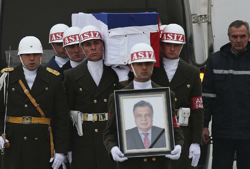 Members of a Turkish honor guard carry the flag-draped coffin of the late Andrei Karlov, Russia’s ambassador to Turkey, with a portrait of him in the lead, during a ceremony at the airport in Ankara, Turkey. Karlov was assassinated Monday.