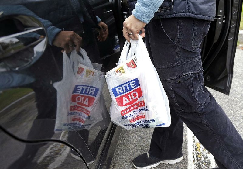 A shopper carries her Rite Aid purchases to her car in North Andover, Mass., this fall. 
