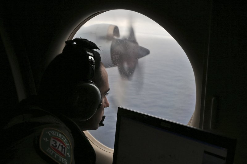 In this March 22, 2014 file photo, flight officer Rayan Gharazeddine scans the water in the southern Indian Ocean off Australia from a Royal Australian Air Force AP-3C Orion during a search for the missing Malaysia Airlines Flight MH370. 