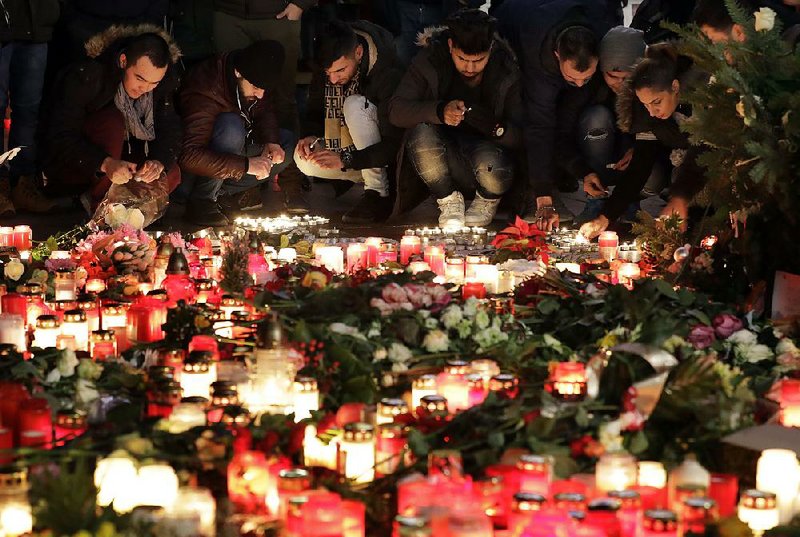 People light candles Wednesday near the Christmas market in Berlin, where 12 people were killed in an attack Monday.
