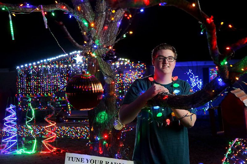 Shane Johnson, 16, shows off his musically coordinated Christmas lights display Wednesday evening on Jupiter Road in Mabelvale. Johnson puts up all of the lights and programs the display.