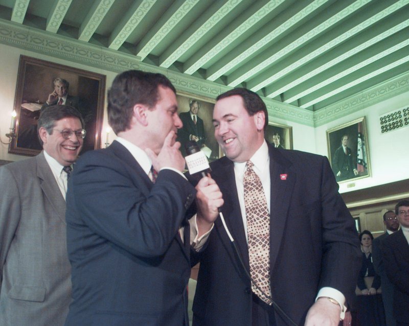 Arkansas Democrat-Gazette/STEVE KEESEE Former Arkansas Governor Mike Huckabee, right, holds the KARN radio&#8217;s microphone up so Sen. John E. Brown, R-Siloam Springs, could answer a reporter&#8217;s question about the passage of the charter school bill that Brown sponsored along with Sen. James Argue, left, on March 29, 1999, during the bill signing in the Governor&#8217;s Conderence Room at the state Capitol.