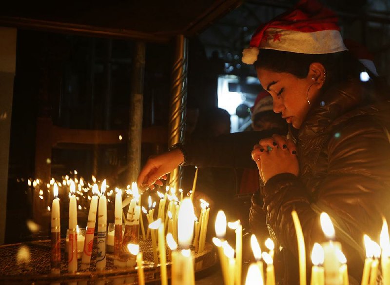 A Christian worshipper in the West Bank town of Bethlehem prays Saturday after lighting a candle on Christmas Eve at the Church of the Nativity, which Christians believe was built on the site where Jesus was born.