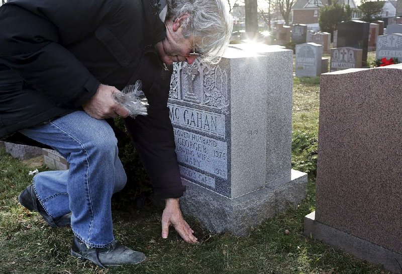 Peter Mattaliano places soil from Ireland at the grave site of George and Mary McGahan in Mount St. Mary Cemetery in New York.