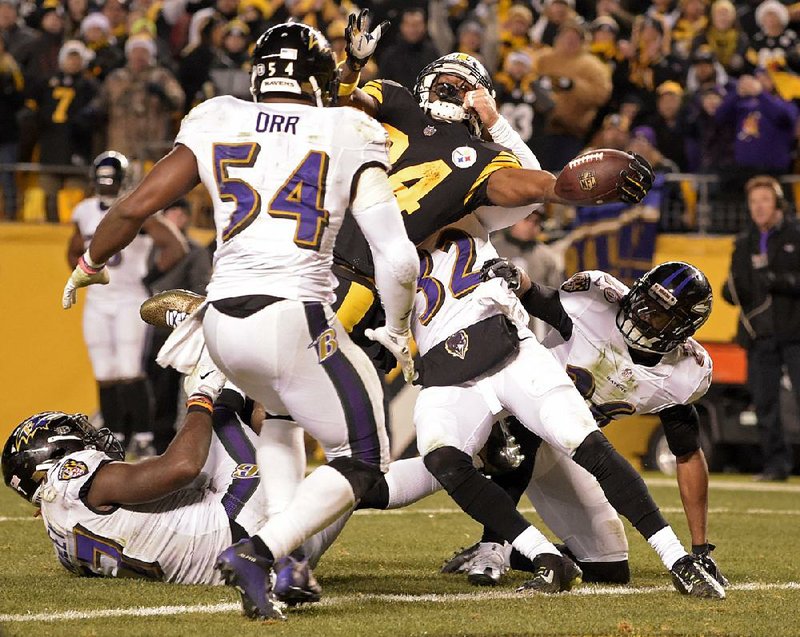 Pittsburgh wide receiver Antonio Brown (center) reaches the ball over the goal line for a touchdown with nine seconds left as the Steelers rallied from a 10-point, fourth-quarter deficit to beat the Ravens 31-27 on Sunday and clinch the AFC North division title.