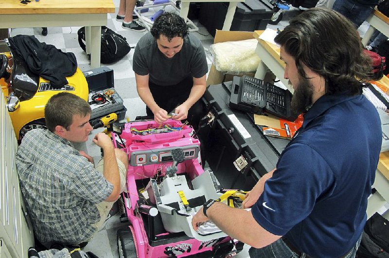 At the University of North Florida in Jacksonville, students Jason Pavichall, (from left) Chris Martin and Garrett Baumann work to customize a toy car to be used by a girl with cerebral palsy.