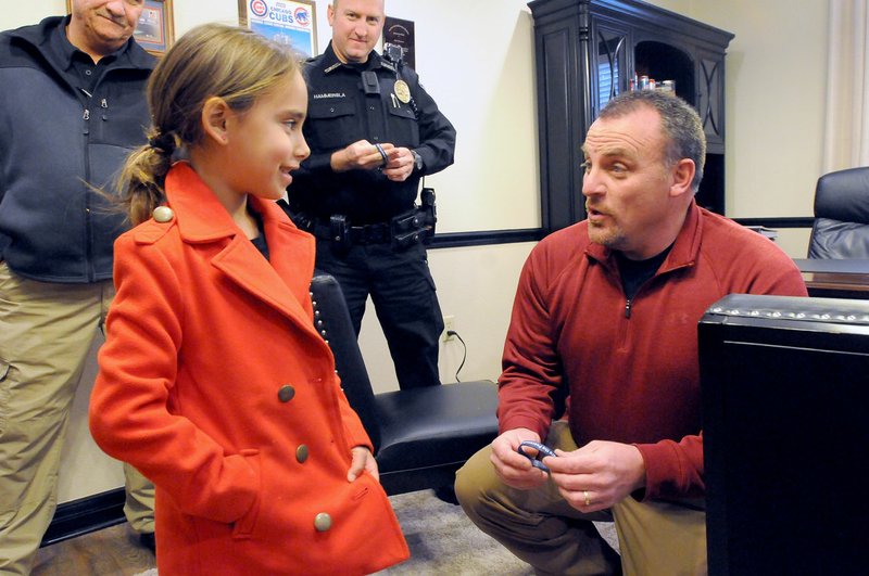 Isabella Johnson, 6, talks Wednesday with Cave Springs Police Chief Rick Crisman after giving him a bracelet