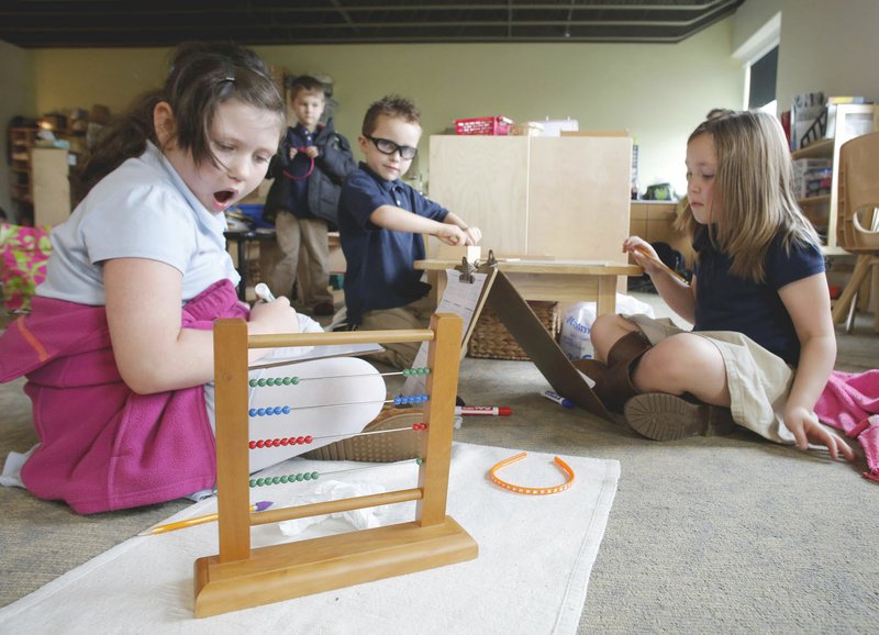 Lila Johnston, Breez Robison and MacKenzie Vanderhaak, all elementary students at Ozark Montessori Academy, use a counting frame Nov. 29, as they work on math problems in a classroom at the Springdale school.