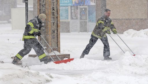 Mandan firefighters Shane Weltikol, left, and Chad Nicklos clear accumulating snow from outside the firehouse in downtown Mandan, N.D., as the Christmas Day blizzard intensifies on Sunday, Dec. 25, 2016. Most of the Dakotas and southwest Minnesota had turned into a slippery mess due to freezing rain Sunday morning before snow arrived later in the day as temperatures fell. 
