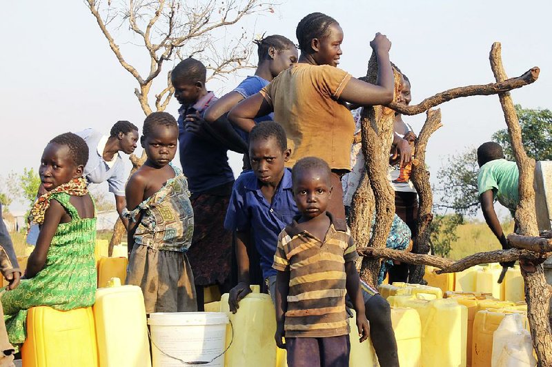 A group of children and adults gather around a bore-hole on Dec. 10 in the Bidi Bidi refugee settlement in Bidi bidi, Uganda.