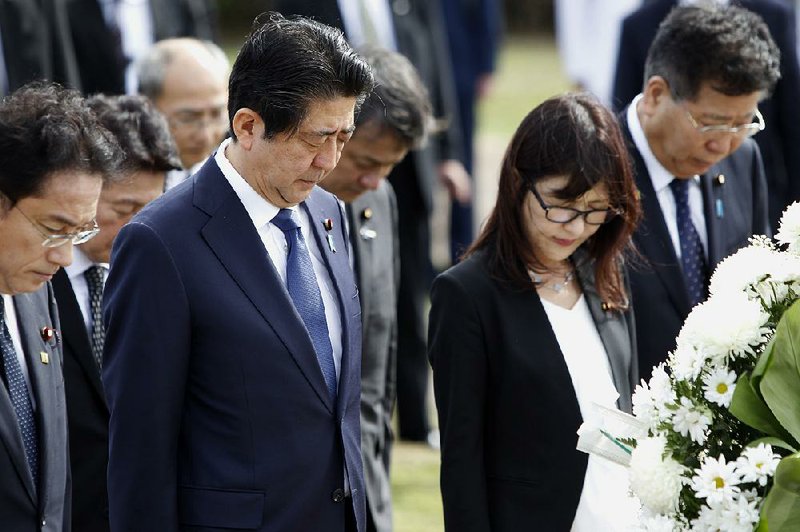 Japanese Prime Minister Shinzo Abe (second from left), Japanese Defense Minister Tomomi Inada and Japan’s Deputy Chief Cabinet Secretary Koichi Hagiuda (right) bow at the Ehime Maru Memorial at Kakaako Waterfront Park, Monday, in Honolulu.