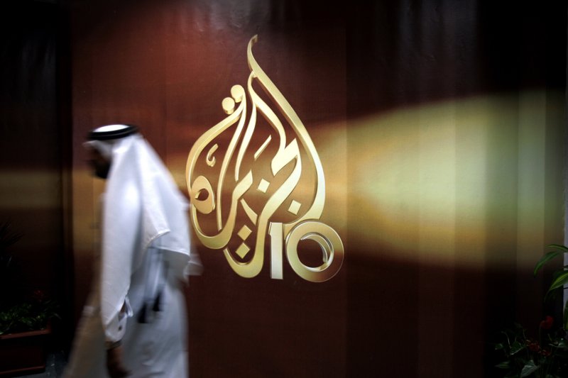In this Wednesday Nov. 1, 2006 file photo, a Qatari employee of Al Jazeera Arabic language TV news channel walks past the logo of Al Jazeera in Doha, Qatar. 