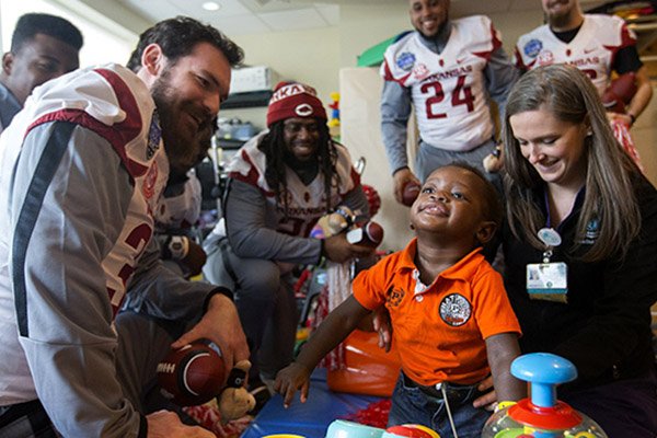 Arkansas football players visit with a patient at the Levine Children's Hospital on Tuesday, Dec. 27, 2016, in Charlotte, N.C.