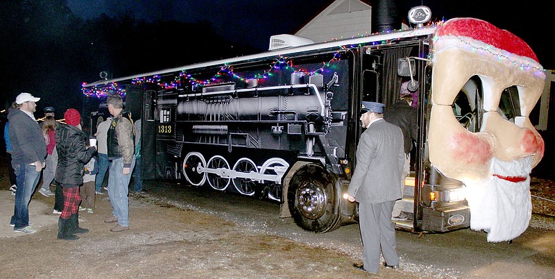 Keith Bryant/The Weekly Vista Guests board the North Pole Express, a Christmas-themed bus to Santa&#8217;s workshop, while Chris McAllister, right, working as the conductor, punching tickets and helping guests board.