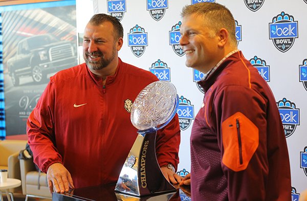 Arkansas coach Bret Bielema, left, and Virginia Tech coach Justin Fuente pose with the Belk Bowl trophy on Wednesday, Dec. 28, 2016, at BB&T Ballpark in Charlotte, N.C.	