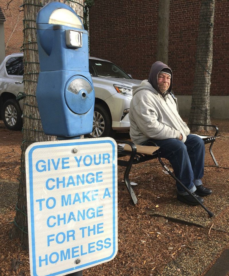 Joe Drury, who said he is homeless, sits near a parking-style meter Tuesday in Annapolis, Md., that is used to collect loose change from those who might otherwise give money to those begging on the street. 