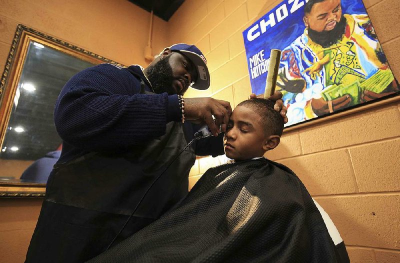 Barber Mike Hutchins gives Xavion Toliver, 7, a trim at Fly Societe Barbershop in Little Rock during Wednesday’s haircut event for boys from the Our House shelter.