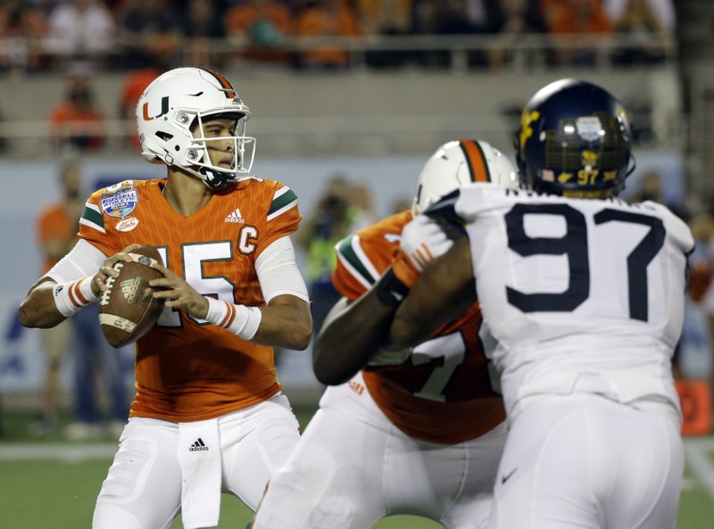 Miami quarterback Brad Kaaya, left, looks for a receiver as he is rushed by West Virginia defensive lineman Noble Nwachukwu (97) during the first half of the Russell Athletic Bowl NCAA college football game, Wednesday, Dec. 28, 2016, in Orlando, Fla. 