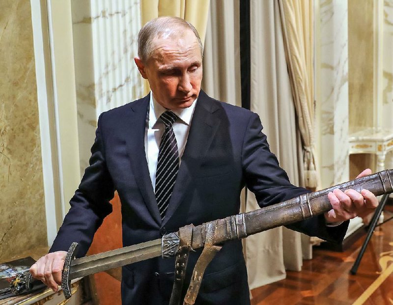 Russian President Vladimir Putin examines a sword Friday in Moscow during a discussion with a Russian TV production team about “ its historical action film about Vikings.