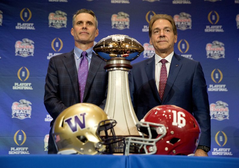 Alabama head coach Nick Saban, right, and Washington head coach Chris Petersen pose for a photo with the trophy during an NCAA college football press conference for the Peach Bowl, Friday, Dec. 30, 2016 in Atlanta. 