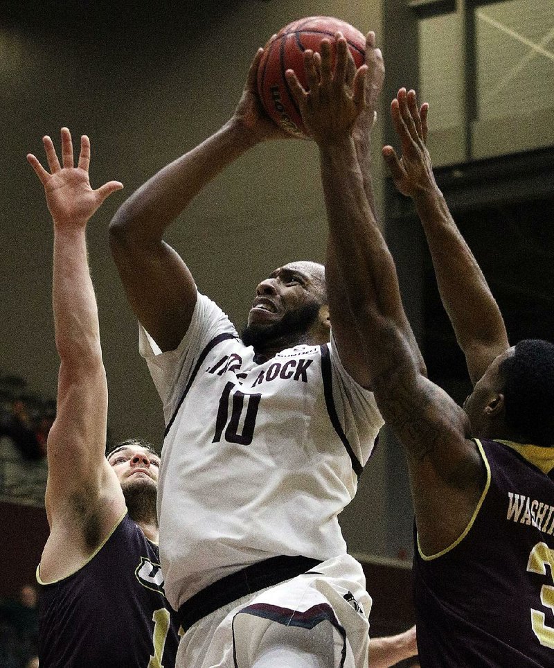 UALR’s Maurius Hill drives between Louisiana-Monroe’s Nick Coppola (left) and Marcus Washington (right) during the Trojans’ 79-75 victory over Louisiana-Monroe on Saturday at the Jack Stephens Center in Little Rock. Hill was the Trojans’ leading scorer with 18 points. 