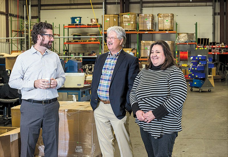 Justin Purkey (left) with his father, Bruce, and sister Robyn Wassman gather at Purkeys facility in Lowell. The family builds electrical systems that help make commercial trucks more efficient. 